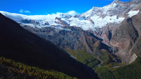 Saastal-Saas-Fee-Switzerland-aerial-drone-glacier-crevasse-beautiful-sunny-fall-autumn-larch-forest-trees-Swiss-Alps-mountain-peaks-glacier-valley-Zermatt-The-Matterhorn-circle-right