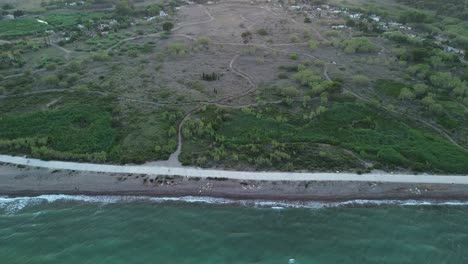 Drone's-top-down-view-of-a-Mediterranean-beach-in-Spain-at-sunset,-with-people-walking-and-exercising-along-the-shoreline-path