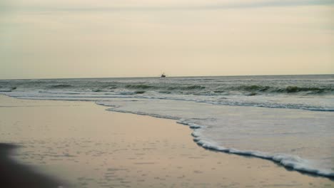 Wellen,-Die-Bis-An-Die-Küste-Reichen,-Mit-Einem-Boot-Am-Horizont