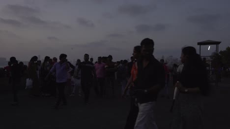 Multitud-De-Turistas-En-La-Playa-De-Marine-Drive-Después-Del-Atardecer-Bajo-Un-Cielo-Tormentoso