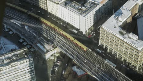 City-train-passing-on-elevated-tracks-next-to-large-buildings,-overhead-shot
