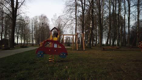 Empy-children-playground-in-the-park,-wind-is-blowing,-toy-car-is-swinging-from-side-to-side