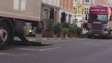 Cars-crossing-the-street-in-the-city-center,-truck-blocks-the-transition-to-another-truck,-Copenhagen,-Denmark