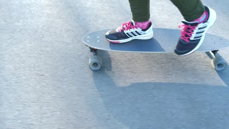 Handheld-Profile-of-sneakers-on-skateboard-moving-on-sidewalk,-alternative-transportation