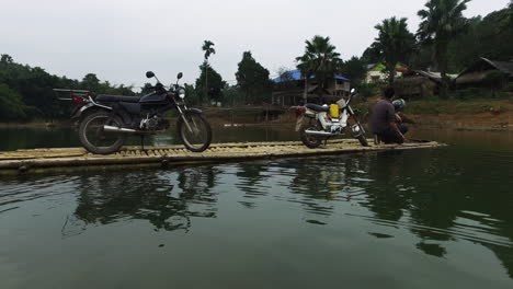 Motorcyclists-crossing-Thac-Ba-Lake-Vietnam-pulling-a-string,-wide-shot