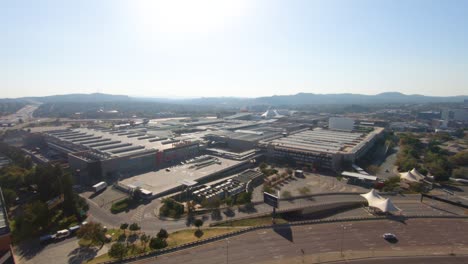 View-of-an-urban-area,-with-buildings-and-a-road-in-the-foreground,-and-in-the-background-some-mountains-under-a-strong-sun