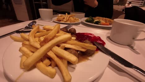 Dinner-at-the-restaurant-served-on-a-white-tray,-french-fries-with-ketchup-and-a-girl-eating-soup-from-a-white-bowl,-static-footage