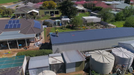 Drone-footage-of-a-workman-or-builder-working-on-a-shed-standing-on-the-roof-at-a-construction-site