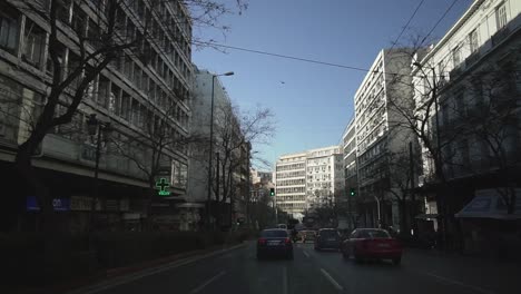 Paseo-En-Coche-En-El-Centro-De-La-Ciudad-De-Atenas-En-Grecia,-Gente-Caminando,-Tráfico-Ligero-En-La-Carretera-Arquitectura-Griega,-Corazón-De-La-Ciudad-Estilo-De-Vida-Urbano-Día-Soleado-De-Verano