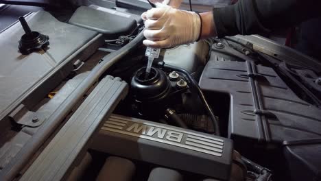 White-male-extracting-fluid-from-power-steering-pump,-static