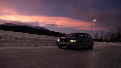 Slow-pan-of-a-bmw-in-the-snow-with-northern-lights-in-the-sky-during-the-sunset