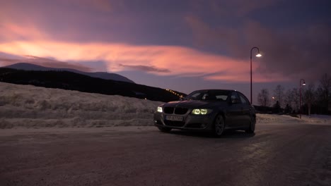 Langsame-Schwenkbewegung-Eines-BMW-Im-Schnee-Mit-Nordlichtern-Am-Himmel-Während-Des-Sonnenuntergangs