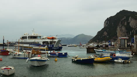 A-cinematic-shot-of-boats-docked-in-Capri,-Italy-while-a-ferry-boat-comes-into-port