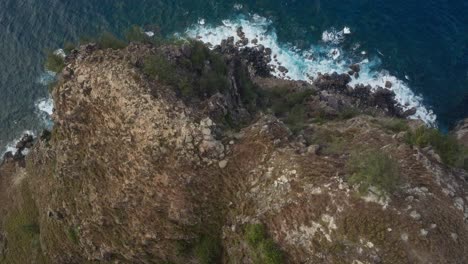 Aerial-top-view-of-rocky-cliff-and-waves-of-pacific-ocean-off-north-coast-of-Maui,-Hawaii