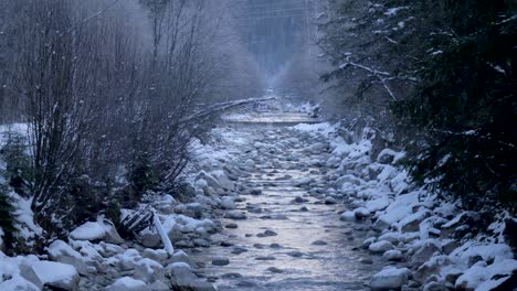 A-misty-mountain-stream-flows-through-a-snowy-landscape