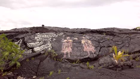 Rock-art,-chalk-drawing-Hawaiian-monarchy-revival-on-lava-rock,-pan-right