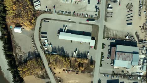 A-slow-spinning,-aerial-view-of-an-industrial-warehouse,-complete-with-trucks-driving-around-below-during-the-autumn-season