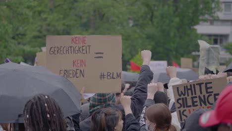 Eine-Menge-Demonstranten-Protestierten-Und-Hielten-Schilder-Gegen-Rassismus-Hoch,-Während-Sie-Bei-Einem-Black-Lives-Matter-Protest-In-Stuttgart,-Deutschland,-Jubelten-Und-Die-Fäuste-Erhoben.