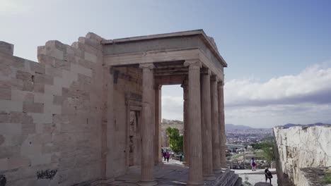 Tilt-down-of-tourists-walking-in-and-out-of-the-Erechtheion-East-porch-at-the-Acropolis-in-Athens-on-a-bright-day-in-November