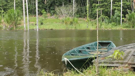 Holzdeck-Mit-Grünem-Boot,-Das-Auf-Dem-See-Schwimmt,-Regenwetter