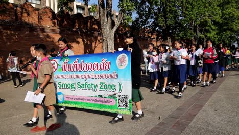 Schulkinder,-Die-Für-Eine-„Smog-Sicherheitszone“-Werben,-Marschieren-Auf-Der-Straße-In-Der-Nähe-Des-Thapae-Tors,-Dem-Wahrzeichen-Der-Stadt-Chiang-Mai,-Um-Die-Behörden-Aufzuklären-Und-Ihnen-Beim-Schutz-Vor-Der-Luftverschmutzungskrise-Zu-Helfen