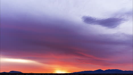 Der-Feurig-Rote-Himmel-Des-Sonnenuntergangs-Mit-Indigoblauen-Wolken,-Die-Darüber-Hinwegziehen---Zeitraffer