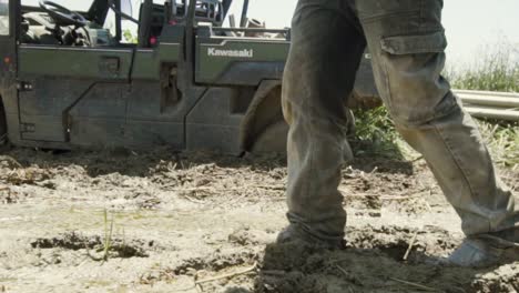 A-farmer-walks-in-the-mud-after-watering-the-field-Slow-motion-shot-Ranger-is-in-the-mud-in-the-background