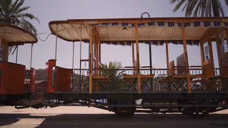 Alte-Orangefarbene-Vintage-Straßenbahn-In-Soller,-Die-An-Einem-Sonnigen-Tag-Vor-Dem-Port-De-Soller-Fährt