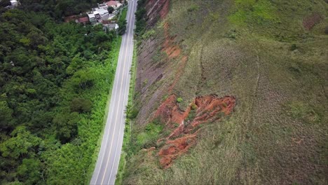 Flyover-above-highway-in-Mendes,-Rio-de-Janeiro-next-to-hill-scarred-by-erosion