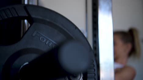 Close-shot-of-weights-being-lifted-by-a-woman-out-of-focus