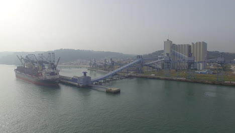 Silos-delivering-cereal-to-a-cargo-ship-at-Lisbon,-Portugal