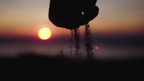 Sand-Rutscht-Aus-Der-Hand-Des-Jungen-Mit-Sonnenuntergang-Im-Hintergrund