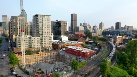 Downtown-Montreal,-drone-shot-descending-on-a-train-leaving-a-station-at-dawn