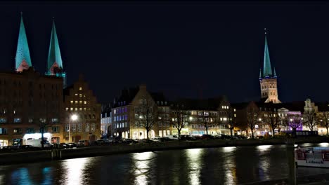 Lapso-De-Tiempo-De-Iglesias-En-Lübeck,-Alemania,-A-Través-De-Un-Canal-Por-La-Noche