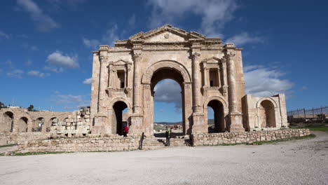 Gente-Tomando-Fotos-Y-Saltando-En-El-Aire-Cerca-Del-Arco-De-Adriano,-Cerca-De-La-Entrada-De-Las-Ruinas-Romanas-De-La-Ciudad-Jordana-De-Jerash.