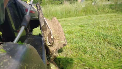 Low-Angle-Shot-of-a-Riding-Lawn-Mower-Cutting-Tall-Grass