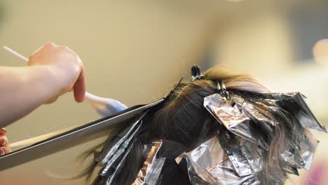 Foil-wraps-applied-to-hair-by-colorist-working-with-client-in-trendy-upscale-salon