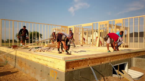 A-drone-shot-floating-around-the-construction-framers-putting-up-walls-on-a-new-home-in-the-process-of-being-built