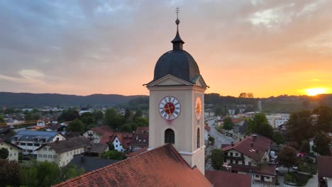 Aerial-orbiting-around-Saint-Lawrence-church-bell-tower-on-a-gorgeous-sunset-in-Feldkirchen-Westerham,-Germany