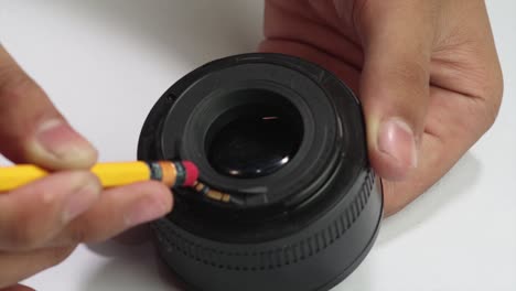 pair-of-male-hands-cleaning-the-inside-of-50mm-canon-dslr-lens-using-pencil's-eraser