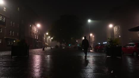 Person-walking-at-empty-Grassmarket-in-Edinburgh-on-a-foggy-quiet-night