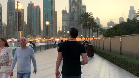 Mid-shot-of-a-European-guy-walking-on-an-illuminated-sidewalk-in-Dubai