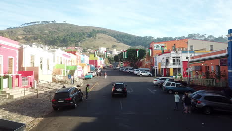 Toma-Aérea-De-Drones-De-Bokaap-Wale-Street-Y-Punto-Verde-Entre-Strand-Street-Y-Rose-Street-En-Ciudad-Del-Cabo,-Sudáfrica-En-Un-Soleado-Día-De-Cielo-Azul