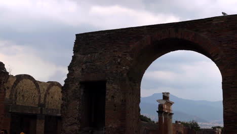 Vista-De-ángulo-Bajo-En-La-Ruina-Del-Arco-Con-Una-Turista-Caminando-Por-Pompeya,-Italia