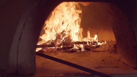 Metiendo-Leña-En-Llamas-Con-Un-Palo-De-Metal-Dentro-De-Un-Horno