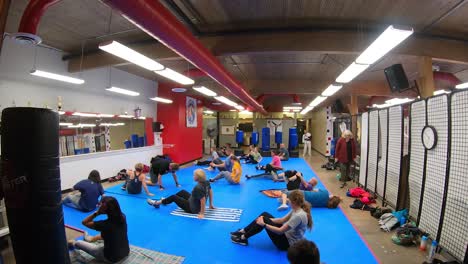 Time-Lapse-of-Adult-students-doing-floor-exercises-while-participating-in-a-self-defense-class-at-martial-arts-school