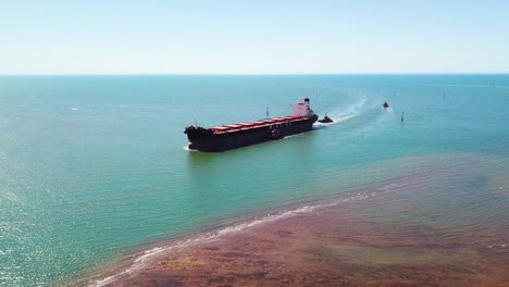 Aerial-wide-shot-of-bulk-carrier-ship-entering-narrow-shallow-port