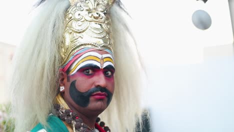 Man-in-Traditional-Indian-Dress-and-Face-Paint-Stares-at-Camera-During-a-Wedding-Ceremony