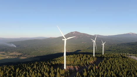 Flying-past-giant-wind-turbines-as-a-small-fire-develops-in-the-distant-mountains