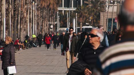 60 fps:-Ein-Typ-Mit-Sonnenbrille-Läuft-Auf-Dem-Boulevard-In-Barcelona,-Umgeben-Von-Vielen-Menschen-–-Gezoomte-Aufnahme